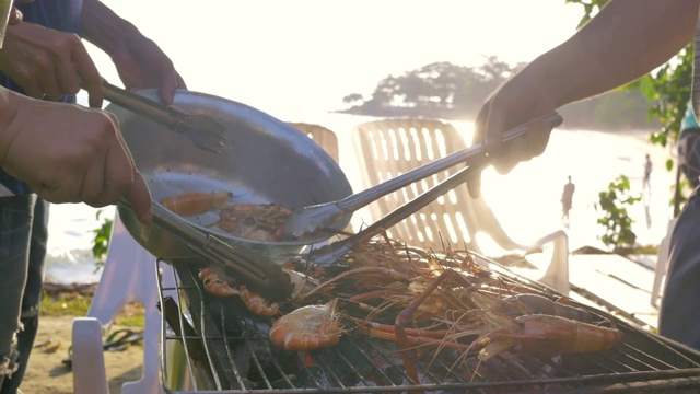 一群朋友在海滩上烧烤猪肉、虾和海鲜聚会活动视频素材