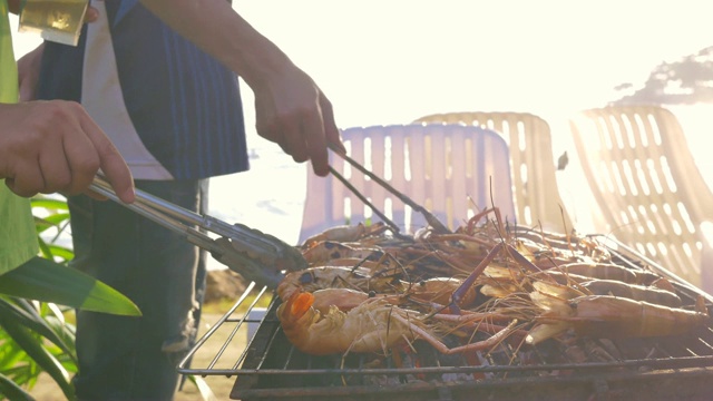 一群朋友在海滩上烧烤猪肉、虾和海鲜聚会活动视频素材