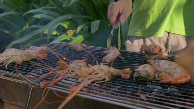 一群朋友在海滩上烧烤猪肉、虾和海鲜聚会活动视频素材