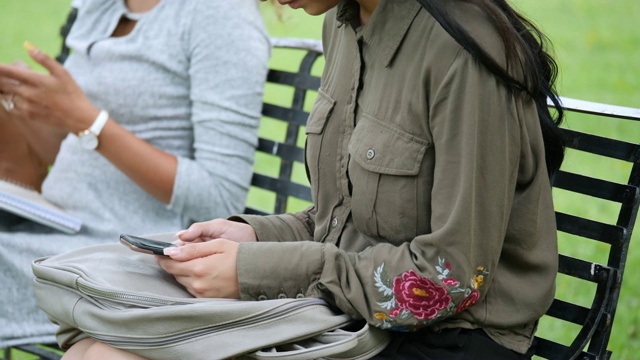 年轻女大学生在校园里在户外使用智能手机视频素材