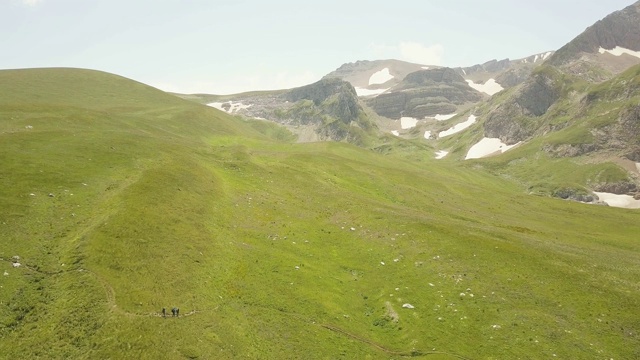 人们走在夏季草地上山谷和山区景观无人机视频素材