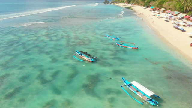 热带海滩绿松石海水和传统船只在巴厘岛，鸟瞰图。视频素材