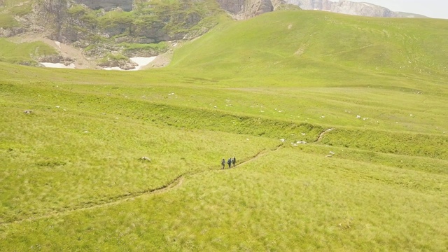 游客徒步在绿色山谷夏季草地上鸟瞰视频素材