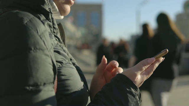 一个年轻女子在繁忙的街道上拿着电话视频素材