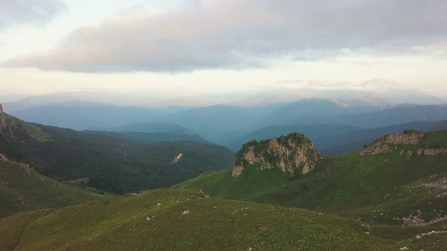 山上的绿色草地和美丽的鸟瞰图上的山峰在天际线视频素材