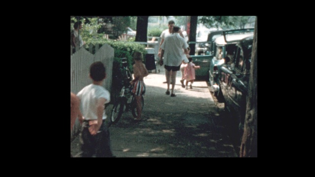 1957年，一个男孩在老爷车旁边骑自行车视频素材