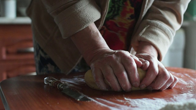 在桌上用面粉揉面团的女人视频素材