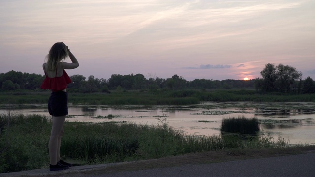 孤独的女孩走在沼泽附近女性正在打电话在夕阳的背景下迷人的年轻女孩讲电话花时间在户外视频素材