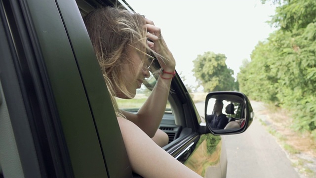 肖像的女孩把她的头伸出车窗靠近风吹女人的头发视频素材