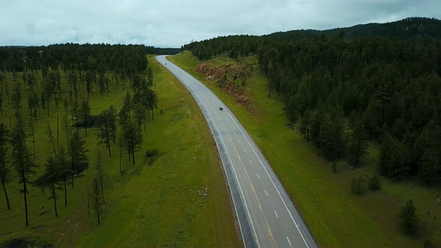 美丽的航拍银汽车行驶在美国公路之间的野生绿色森林，岩石山与树木。视频素材