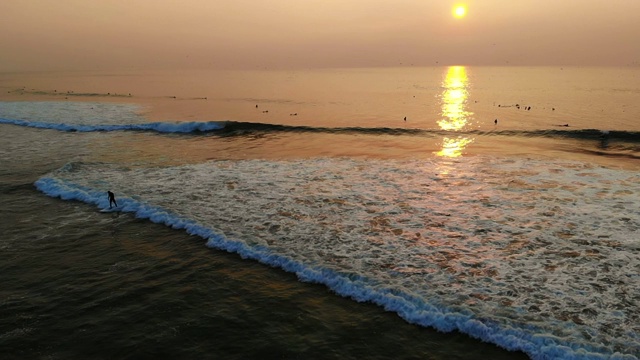 夕阳西下时，冲浪者在海洋海滩上乘风打浪。视频素材