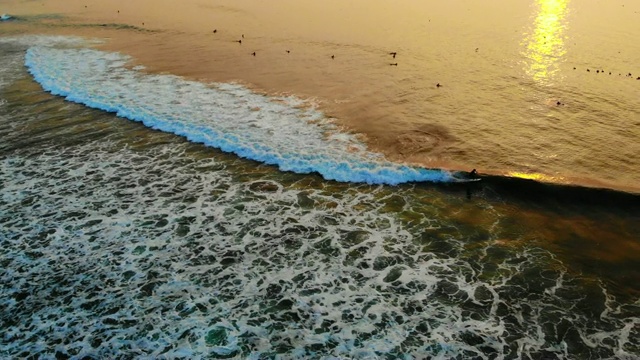 夕阳西下时，冲浪者在海洋海滩上乘风打浪。视频素材