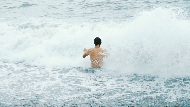 海浪覆盖着一个沐浴在暴风雨中的快乐的人视频素材