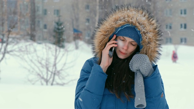 年轻漂亮的女人在冬天下雪的室外打电话。视频素材