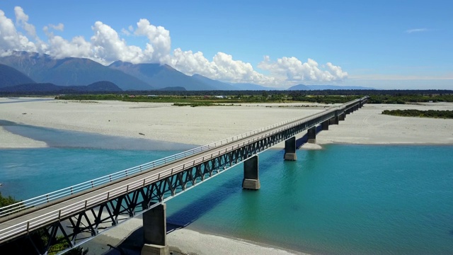 鸟瞰图横跨蓝色河流的公路桥与山风景在夏季的西海岸在南岛，新西兰。视频素材