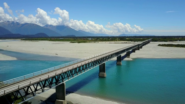 鸟瞰图横跨蓝色河流的公路桥与山风景在夏季的西海岸在南岛，新西兰。视频素材