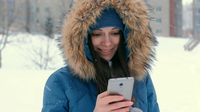 年轻漂亮的女人在她的手机上输入信息，然后看着镜头和微笑。视频素材