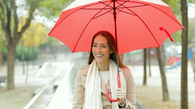 快乐的女人撑着伞在雨中行走视频素材