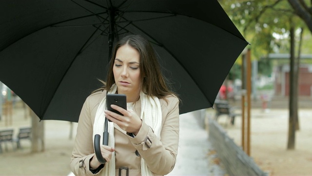 沮丧的女人在下雨时查看天气应用视频素材