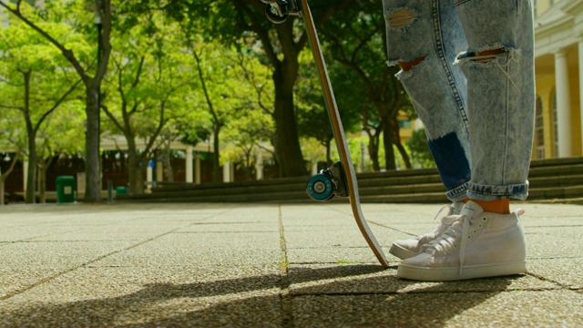 带着滑板的年轻女子站在城市里视频素材