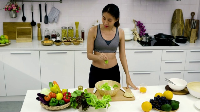 年轻的亚洲运动女性正在准备沙拉和在厨房跳舞，健康食品的概念视频素材