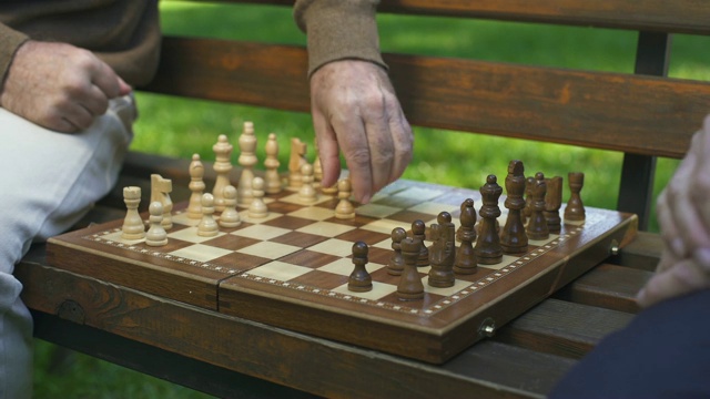 爷爷们在长凳上下棋，棋子在棋盘上移动，游戏开始了视频素材