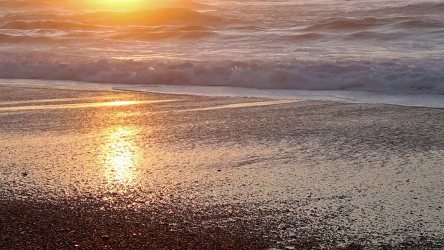 长焦镜头直接射向太阳的海浪撞击太平洋海滩在金色的日落。视频素材