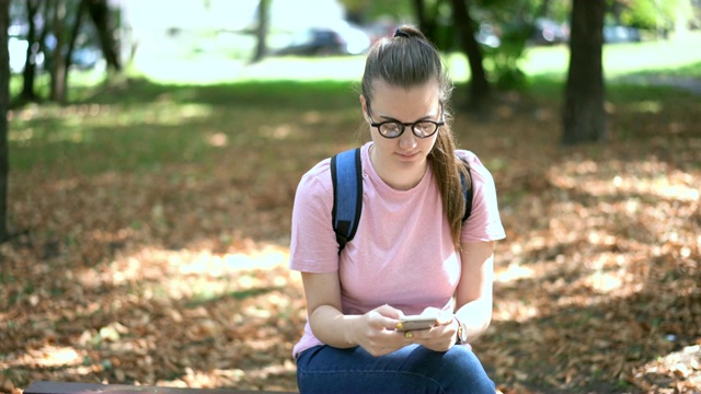 一个年轻女人在公园里用手机发短信视频素材