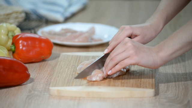 在桌子上切鸡胸肉的女人。视频素材