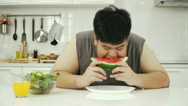 正面视图:泰国超重男子吃西瓜等健康食品时感到饥饿视频素材