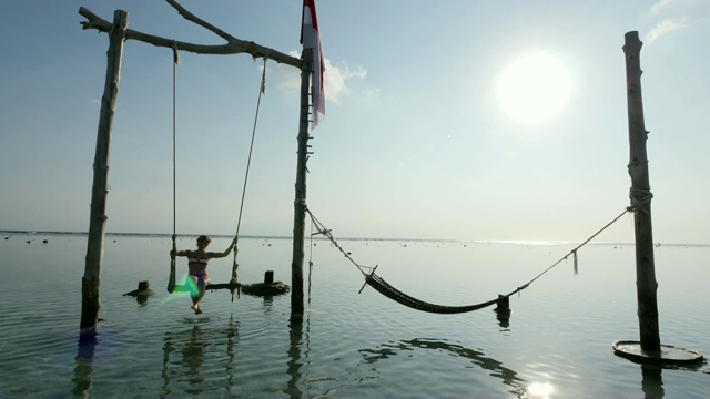 在巴厘岛的Gili Trawangan岛的海滩上荡秋千的女孩视频素材