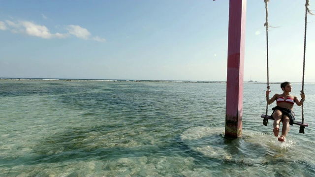 在巴厘岛的Gili Trawangan岛的海滩上荡秋千的女孩视频素材