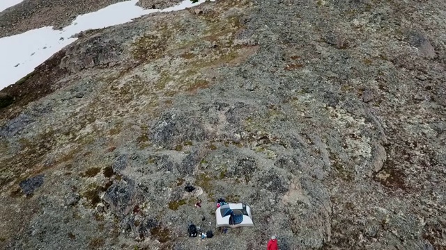 无人机:在长满苔藓的雪山上的人和帐篷视频素材