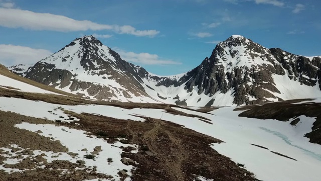 无人机:两名男子徒步走向积雪覆盖的山脉视频素材