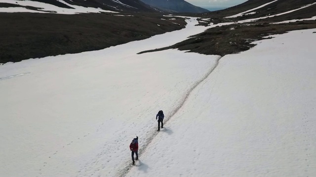 无人机:两个人徒步穿越雪山视频素材