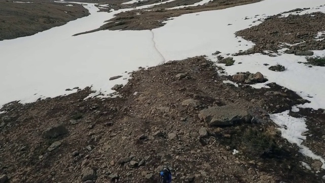 无人机:男人在岩石，雪山地形上奔跑视频素材