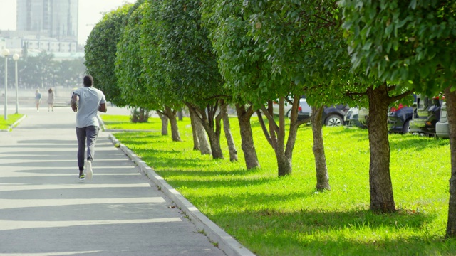 一名非洲男子在夏日沿着城市大道慢跑视频素材