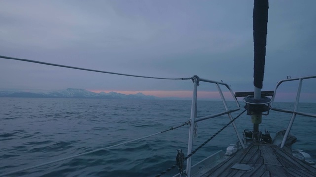 船在海上航行，夕阳在黄昏的天空和雪山的背景视频素材