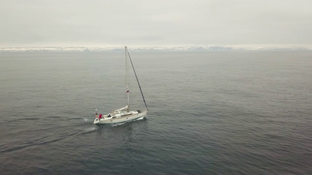 航行游艇漂浮在海上和雪域岛屿和高地上的天际线无人机视图视频素材