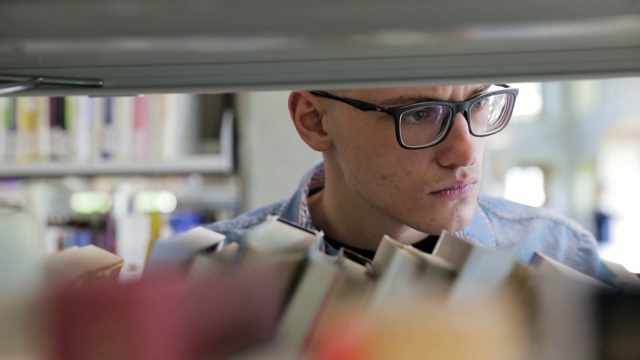 一名男子在大学图书馆的书架上找书视频素材