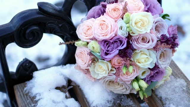 特写，美丽的婚礼玫瑰花束牛奶，白色和丁香。花束躺在公园里白雪覆盖的长凳上。冬季婚礼视频素材