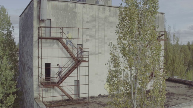 在一座废弃的混凝土建筑里，空中射击追着女孩上楼梯的人。空中拍摄的男子追赶女子上楼到废弃的混凝土建筑的屋顶。视频下载