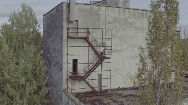 在一座废弃的混凝土建筑里，空中射击追着女孩上楼梯的人。空中拍摄的男子追赶女子上楼到废弃的混凝土建筑的屋顶。视频下载