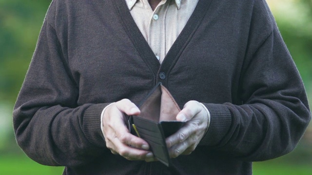 一名男子向照相机展示空钱包，高物价和低生活工资，贫困视频素材