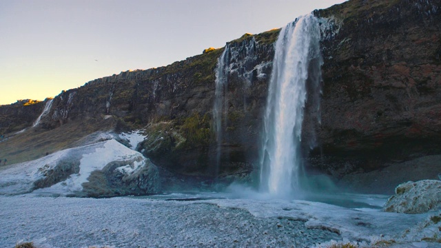 seljalandsfoss，冰岛雷克雅未克附近黄金圈最著名的瀑布之一。高高的玄武岩悬崖上有一条小溪。冬天所有地面上的叶子和草都冻上了冰视频素材