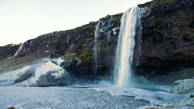 seljalandsfoss，冰岛雷克雅未克附近黄金圈最著名的瀑布之一。高高的玄武岩悬崖上有一条小溪。冬天所有地面上的叶子和草都冻上了冰视频素材