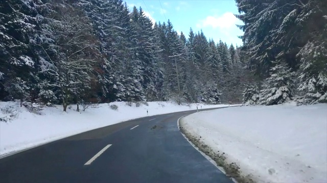 在寒冷的冬天的早晨，在积雪的路上穿过森林视频素材