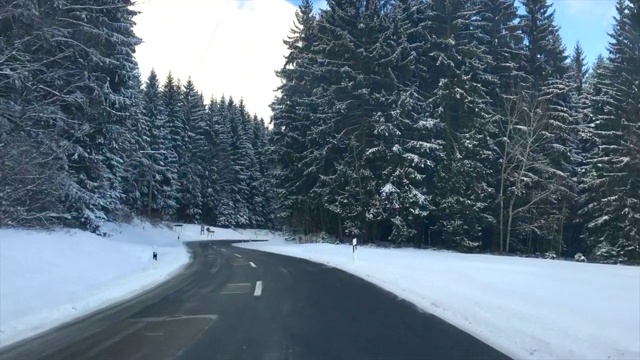 在寒冷的冬天的早晨，在积雪的路上穿过森林视频素材