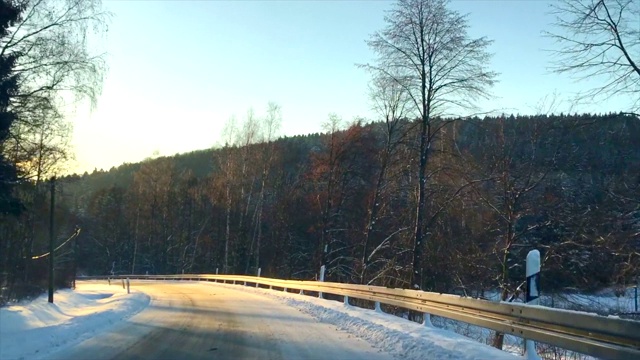 在寒冷的冬天的早晨，在积雪的路上穿过森林视频素材