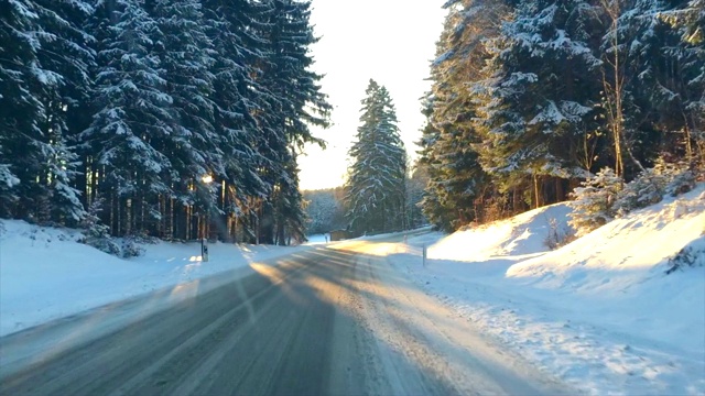 在寒冷的冬天的早晨，在积雪的路上穿过森林视频素材